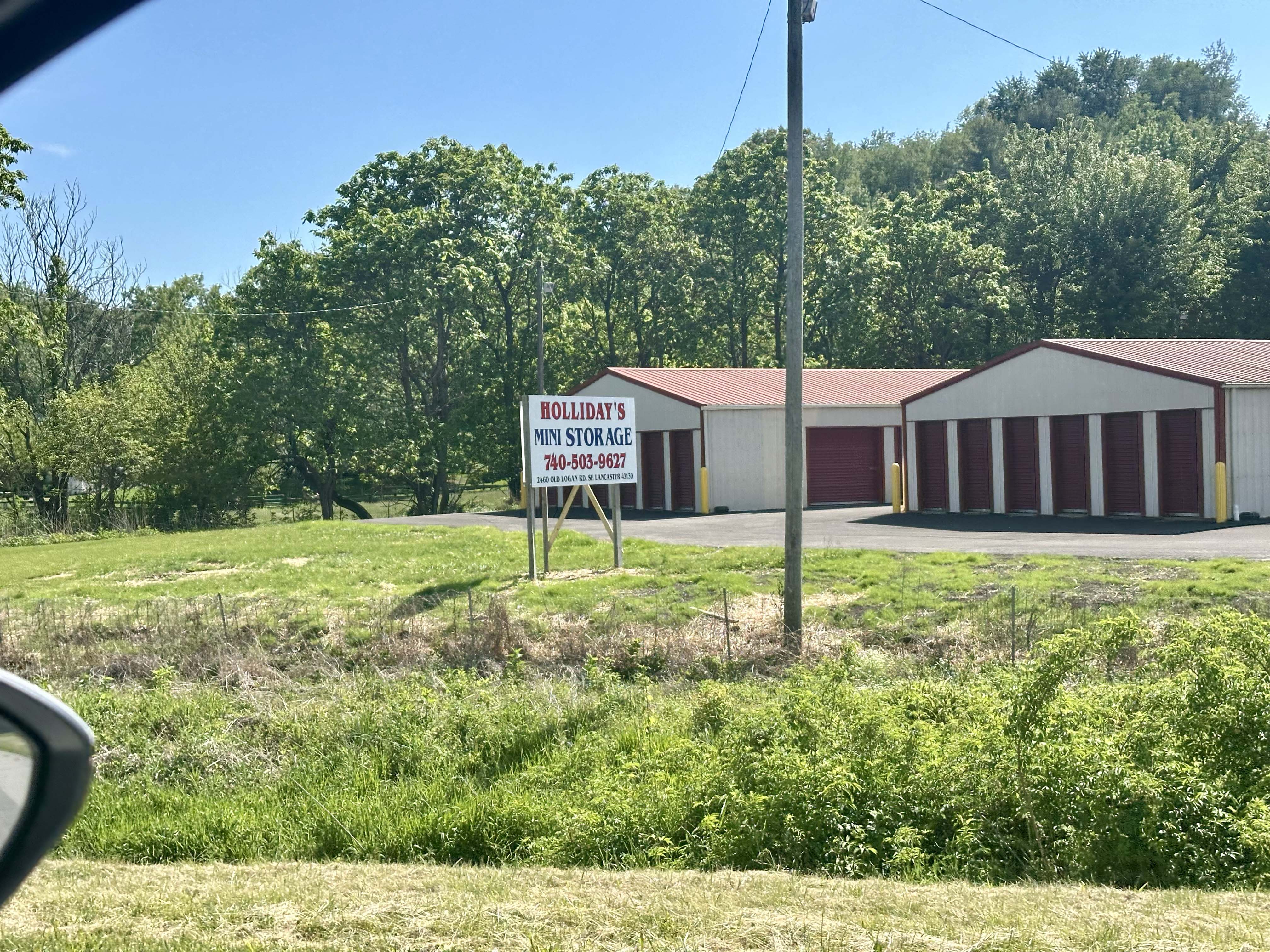 Holliday's Mini Storage signage on main building at 2460 Old Logan Rd SE, Lancaster OH, with numbered storage units below.